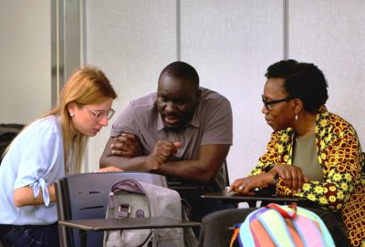 Three students collaborate in a classroom.