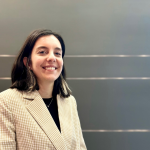 A woman smiles at the camera in front of a gray background.