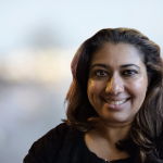 A woman in a black shirt smiles at the camera.