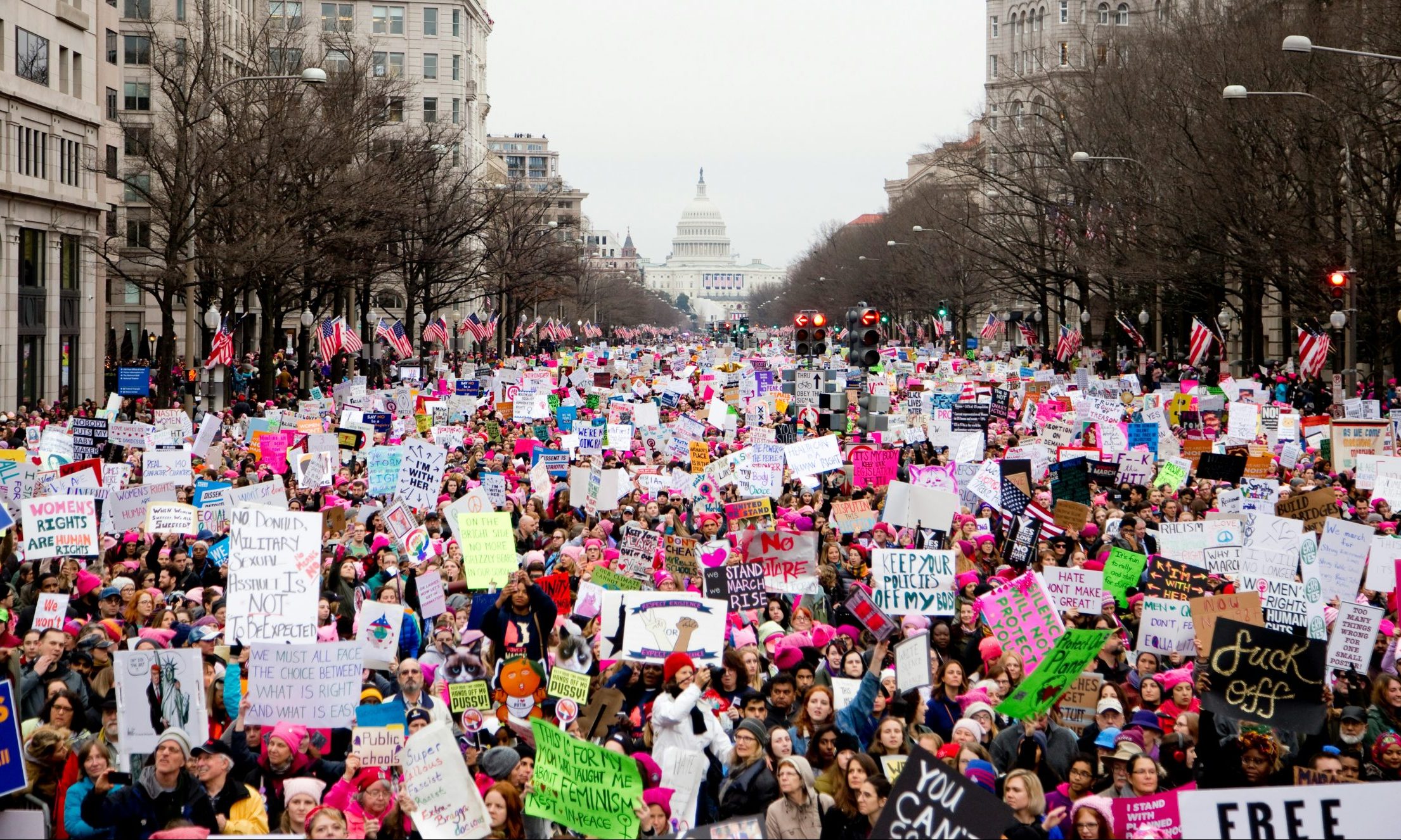 Thousands of people protest by packing a street and holding signs.