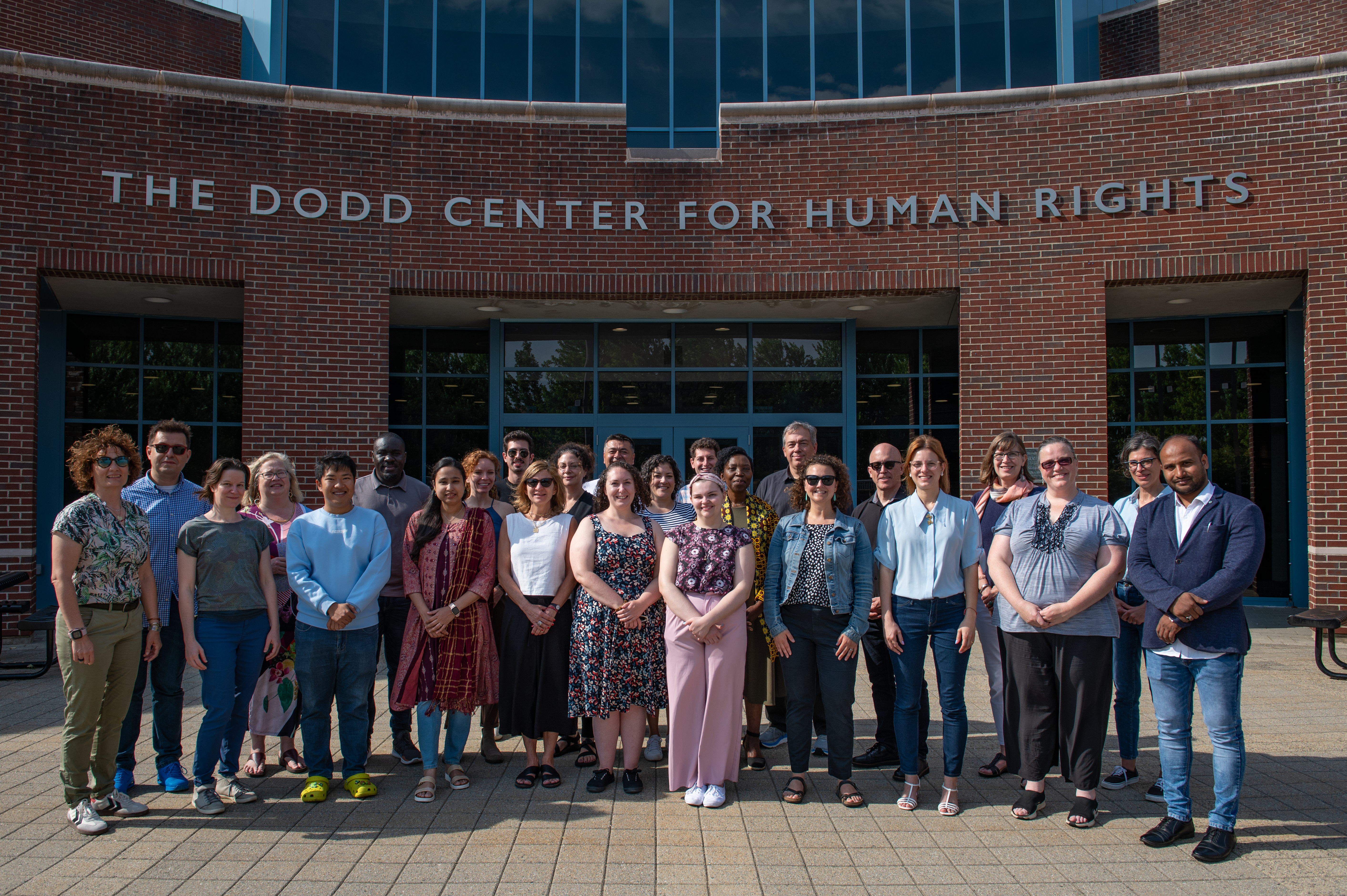 A group of people attending the Scheidt Family Seminar on Genocide Studies and Prevention stand together in front of the The Dodd Center for Human Rights